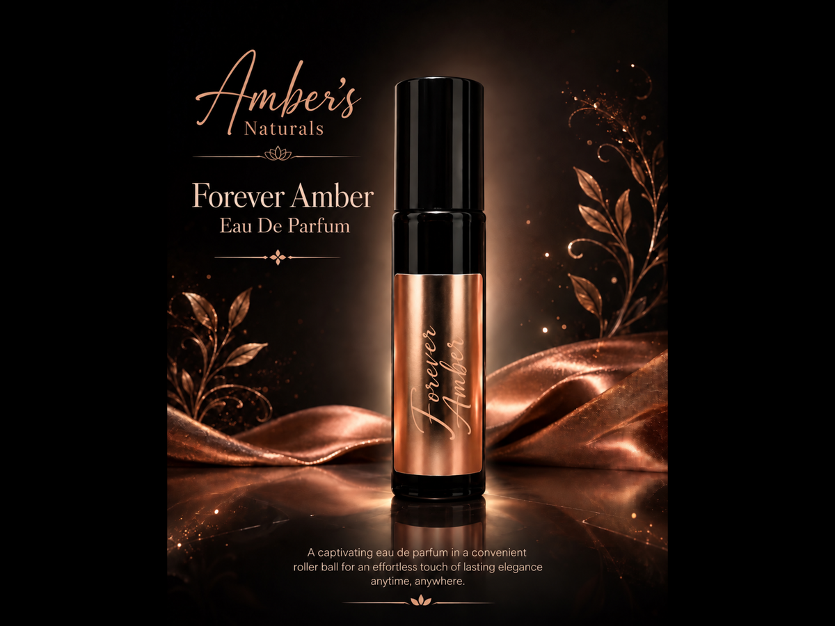 A perfume roller bottle labeled 'Forever Amber' by Amber's Naturals, shown against a dark brown background with metallic rose-gold draped fabric and decorative gold leaf graphics.