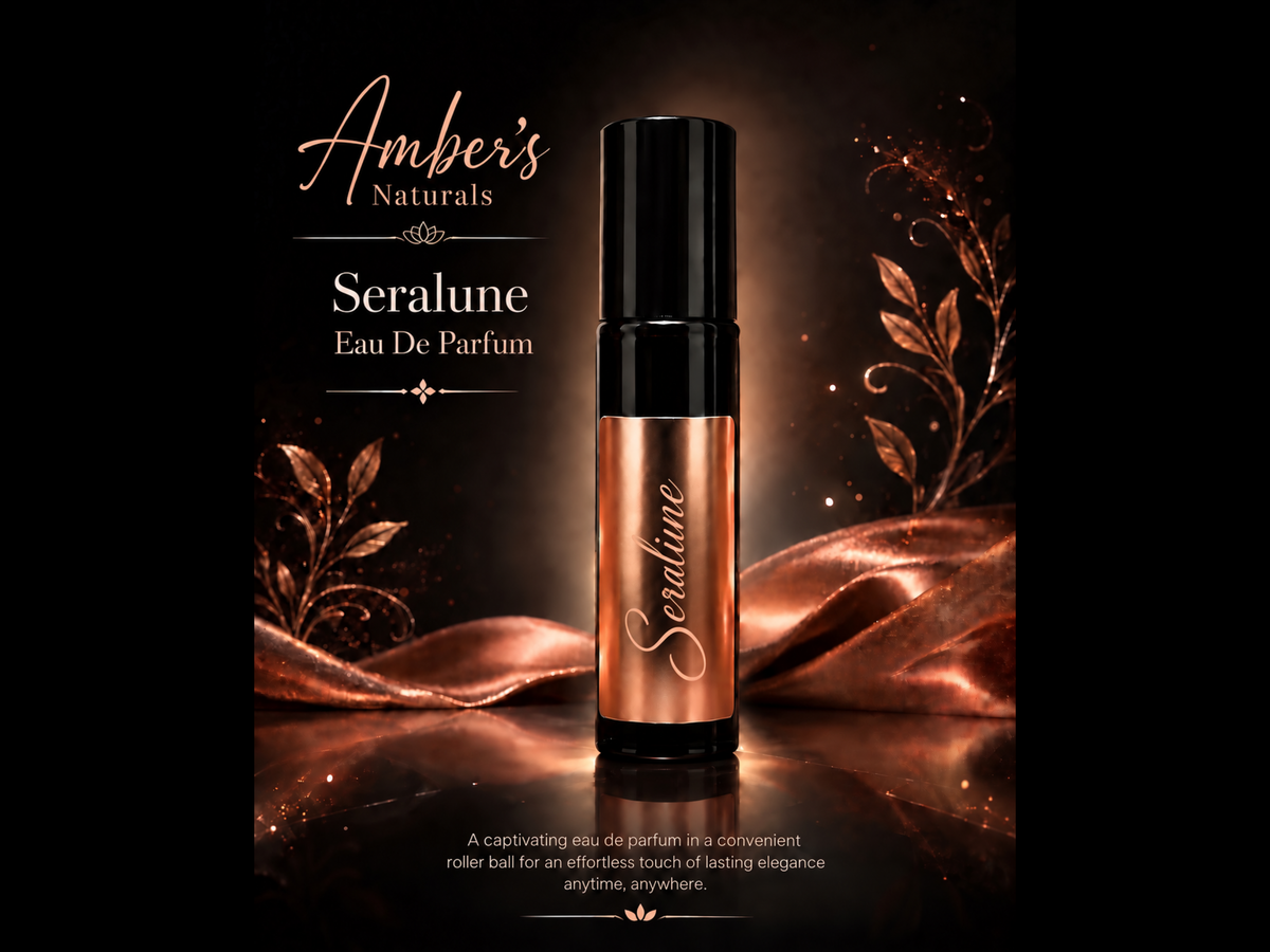 A perfume roller bottle labeled 'Seralune' by Amber's Naturals, shown on a dark reflective surface with metallic rose-gold draped fabric and decorative leaves. The bottle has a black cap and a metallic rose-gold body with the brand name in white script.